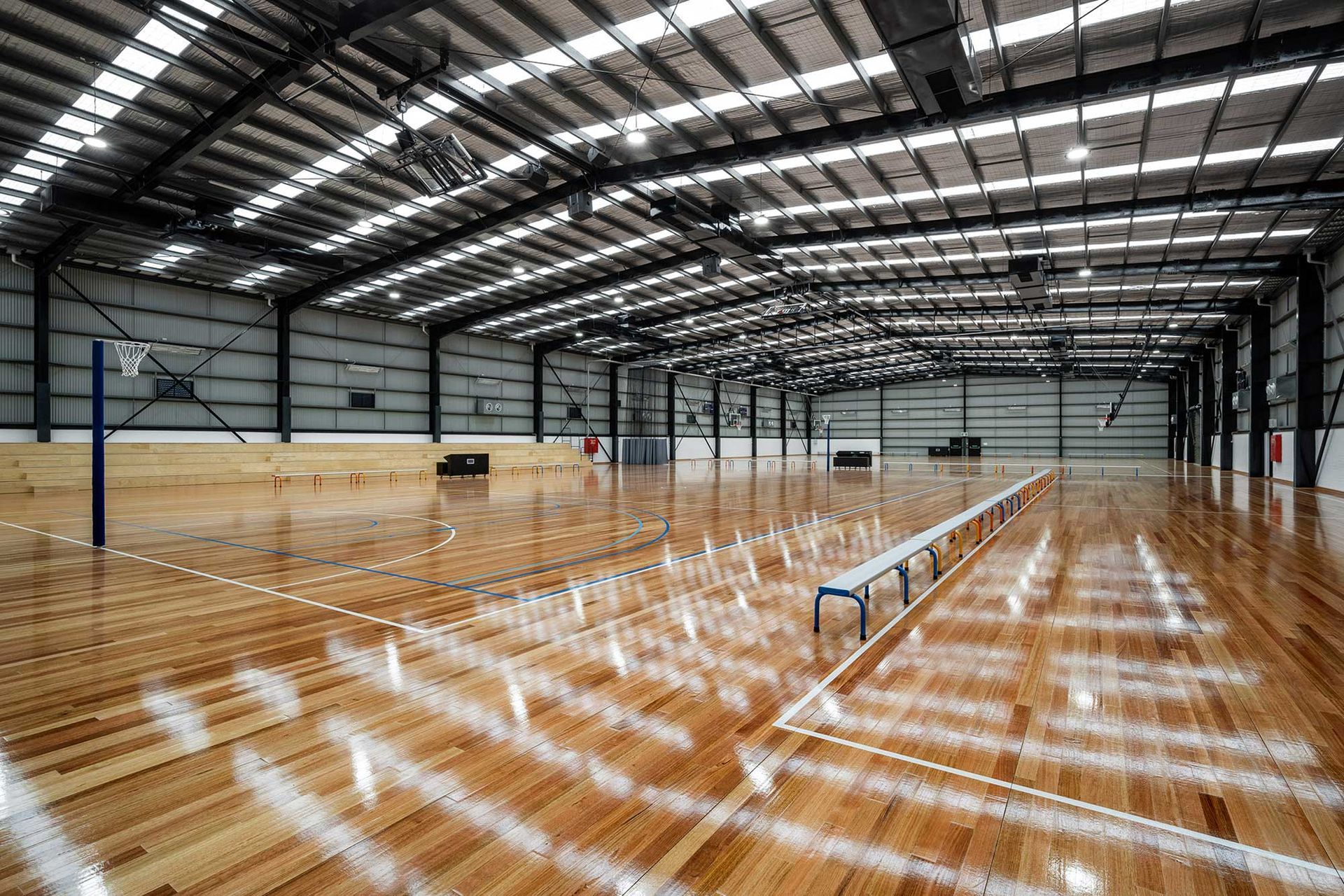 A large indoor basketball court with a wooden floor and benches.
