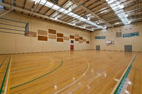 Indoor basketball court featuring polished wooden floors and a high ceiling.