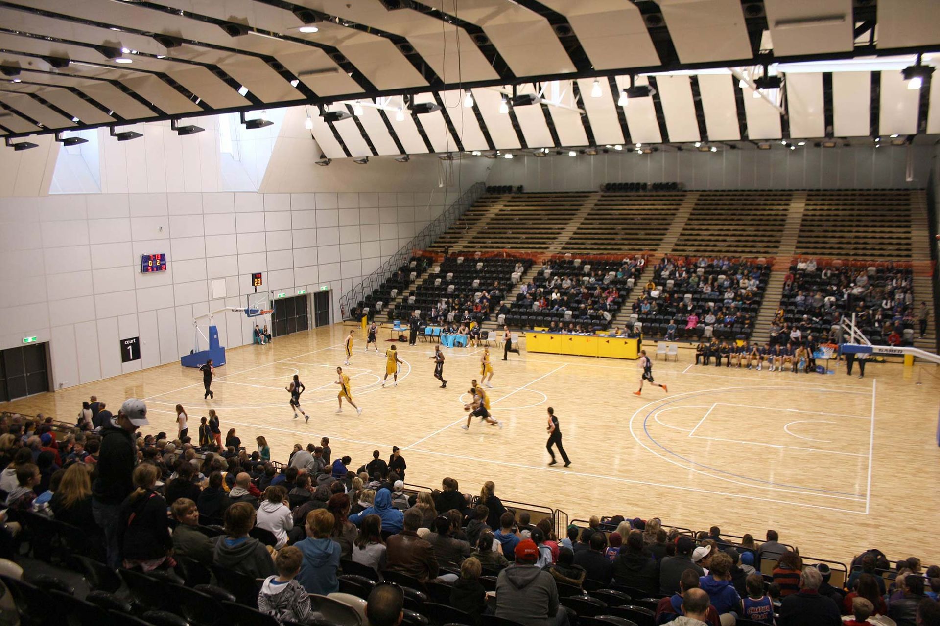 A crowd of people are watching a basketball game in a stadium.