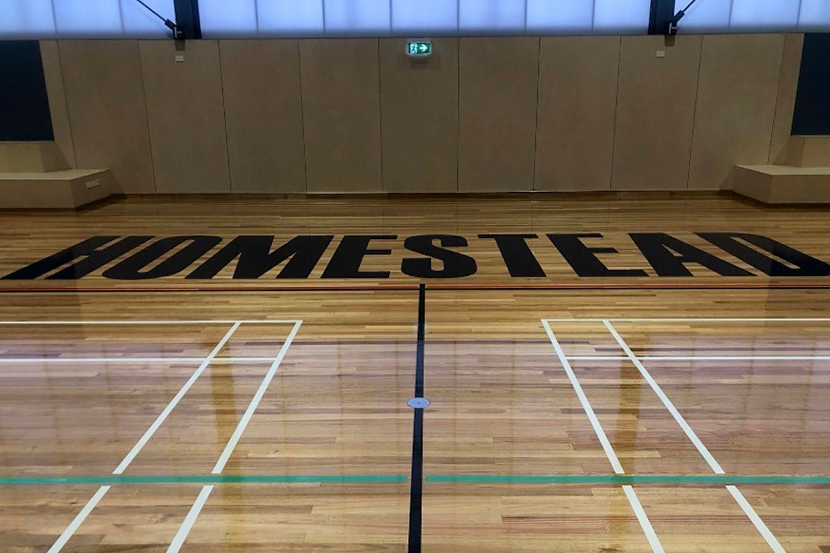The word homestead is painted on the floor of a gym