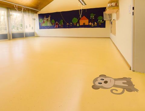 A room with a monkey on the floor and a mural on the wall.