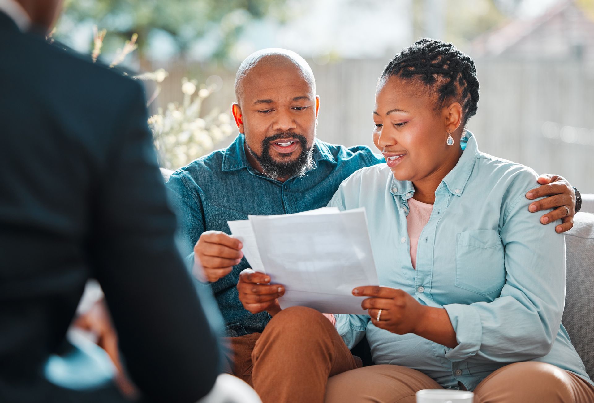Couple reviewing documents with an advisor, discussing finances, outdoors.