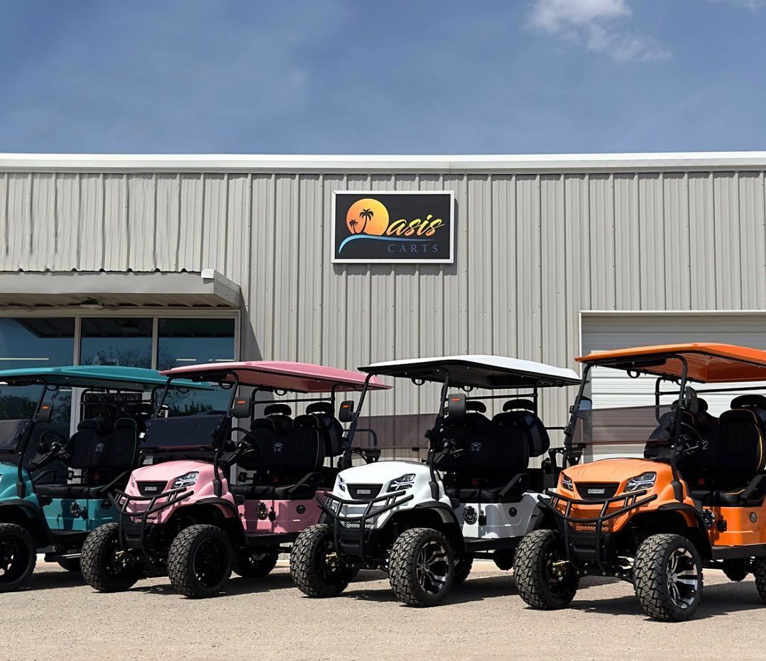 A row of golf carts are parked in front of a building.