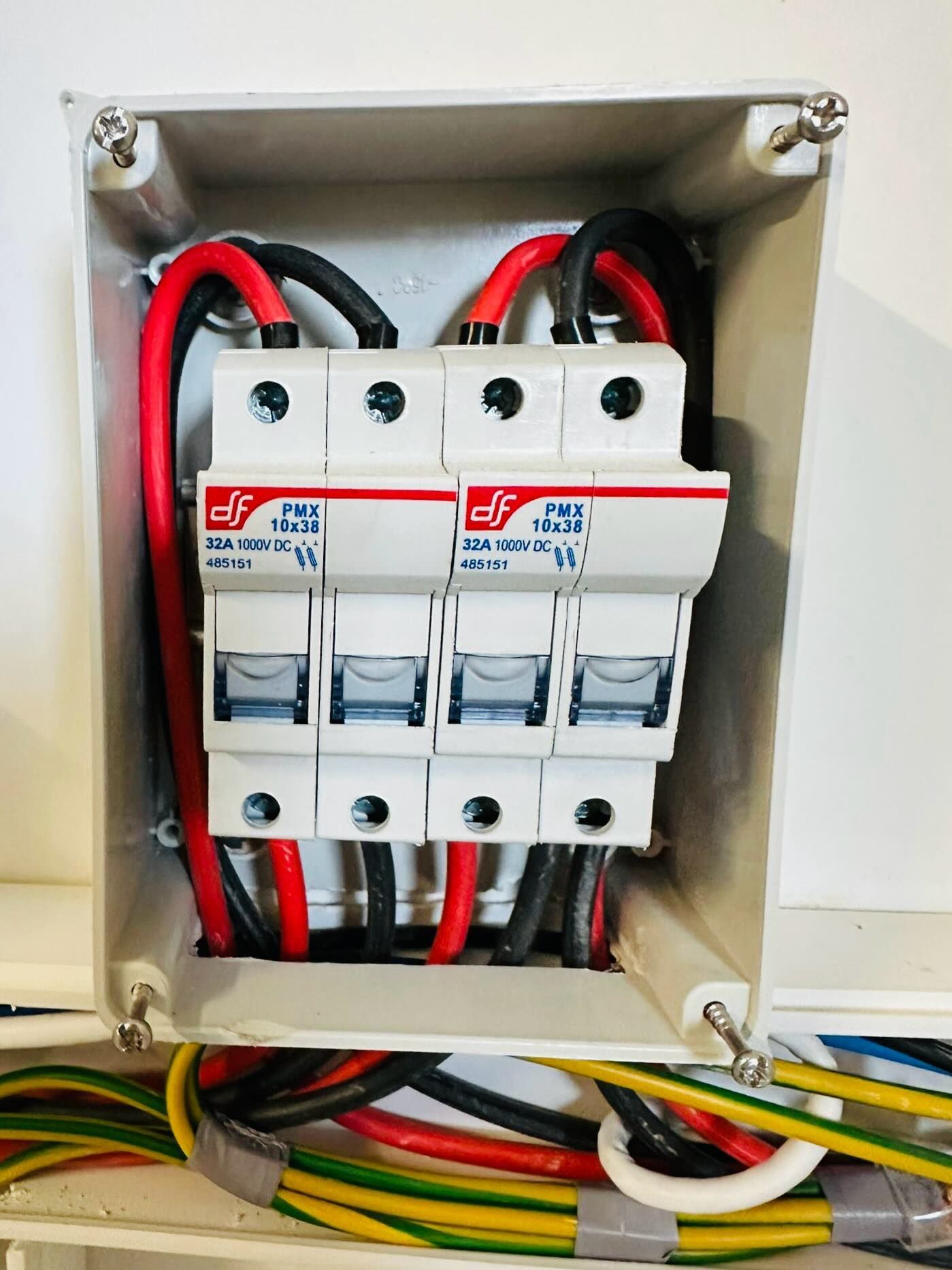 Scatola portafusibili elettrica con fili rossi e neri all'interno di un involucro bianco.