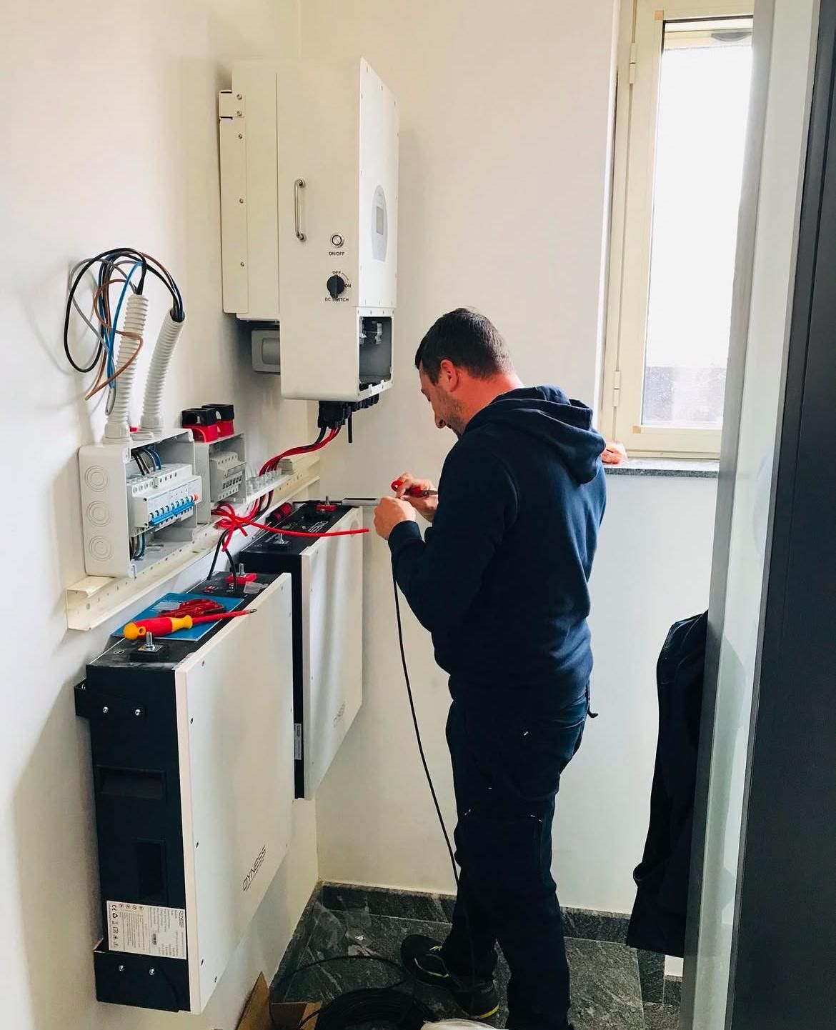 Persona che utilizza spelafili per lavorare sui cavi elettrici all'esterno di un edificio.