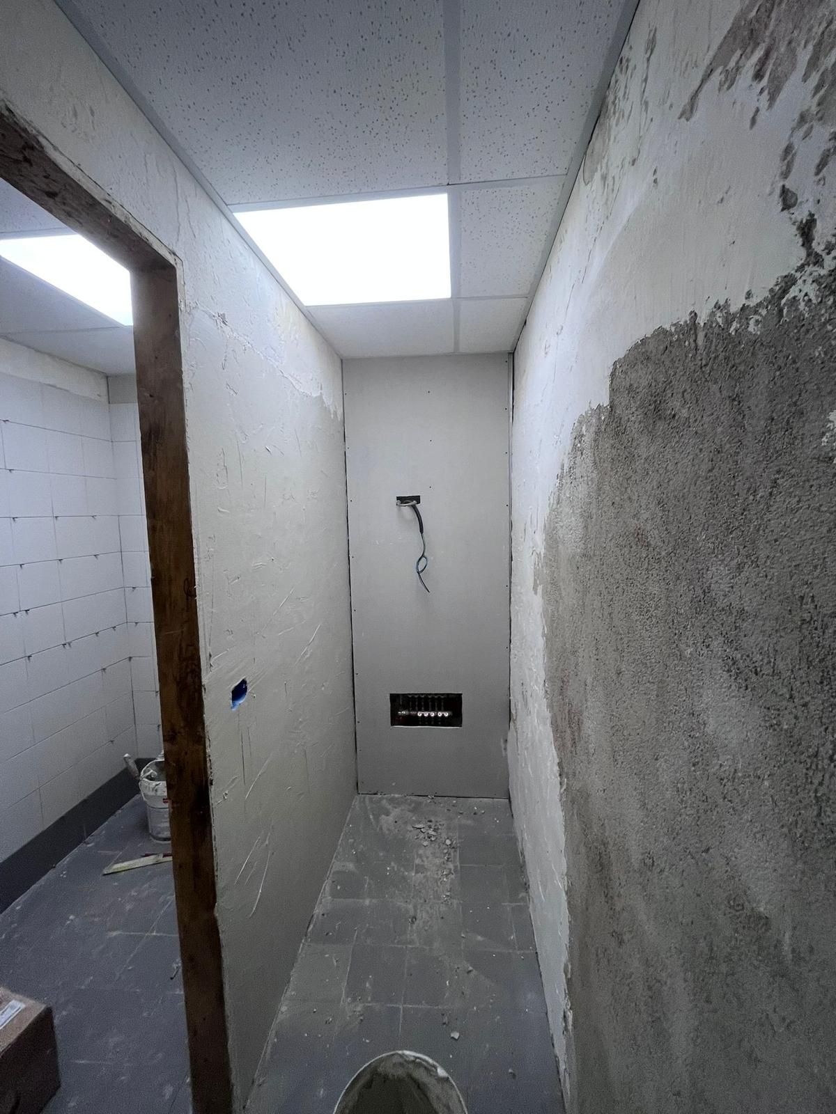 Cantiere: impalcature vicino a un magazzino, nastro di sicurezza e segnaletica, cielo coperto.