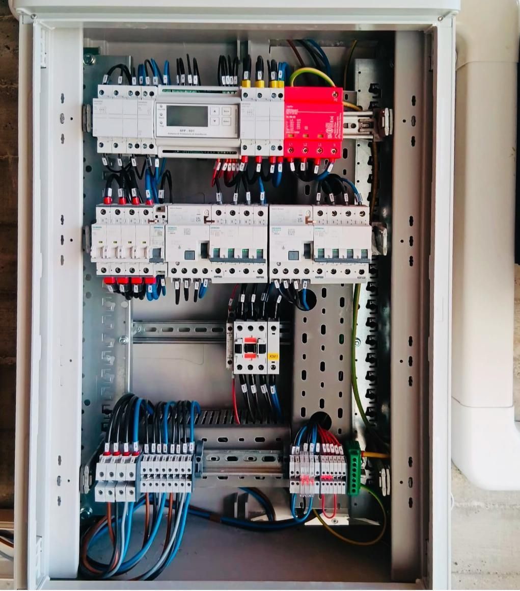 Scatola portafusibili elettrica con interruttori automatici dietro un coperchio di plastica trasparente.