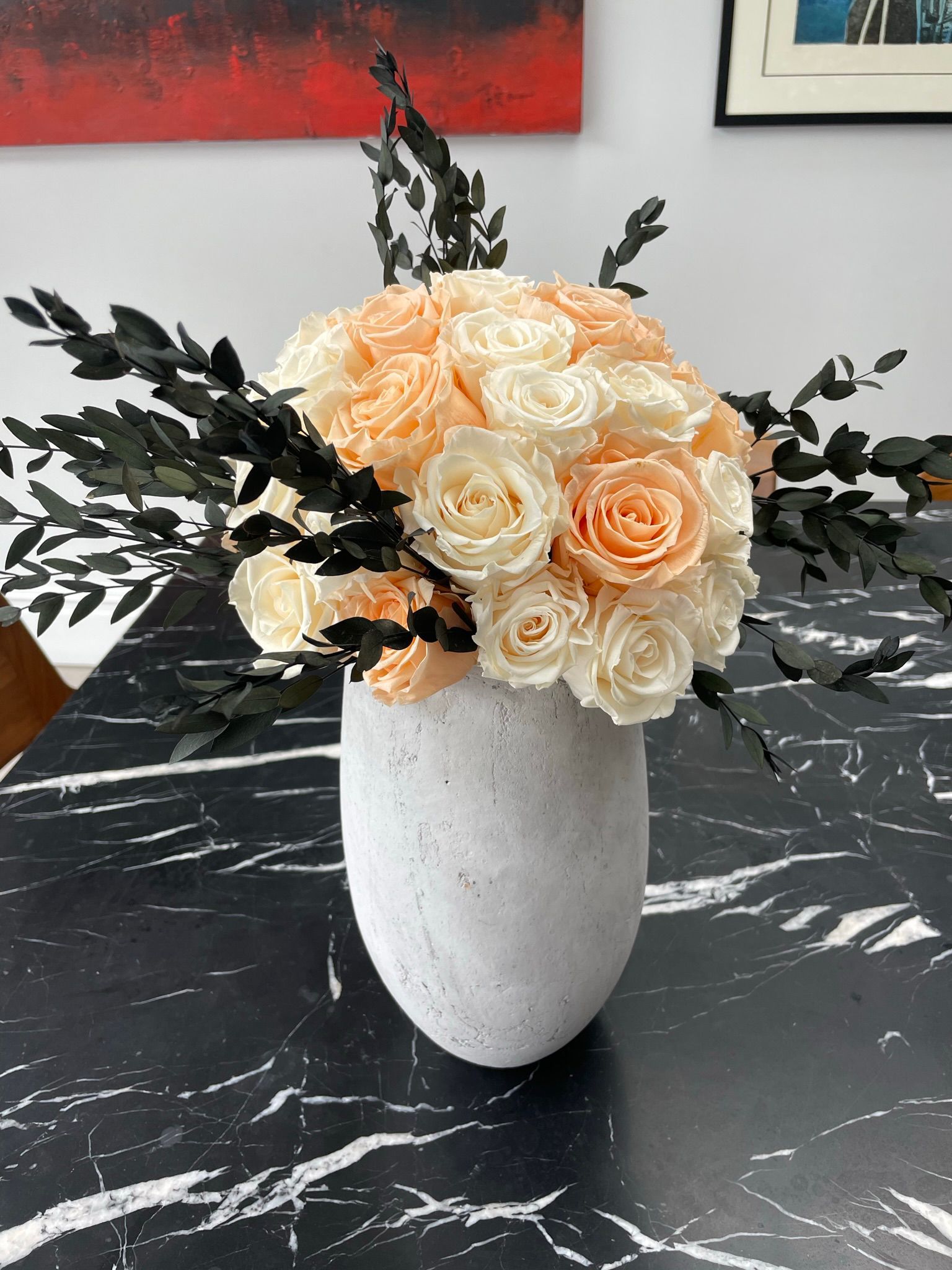 Bespoke arrangement, White vase with peach and white roses, accented by dark leaves,
