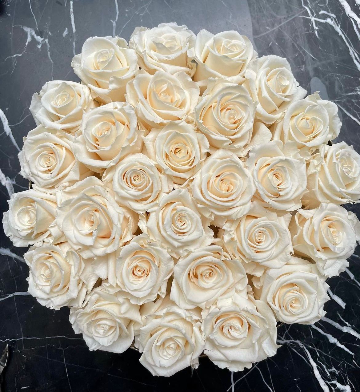A circular arrangement of many white preserved roses.