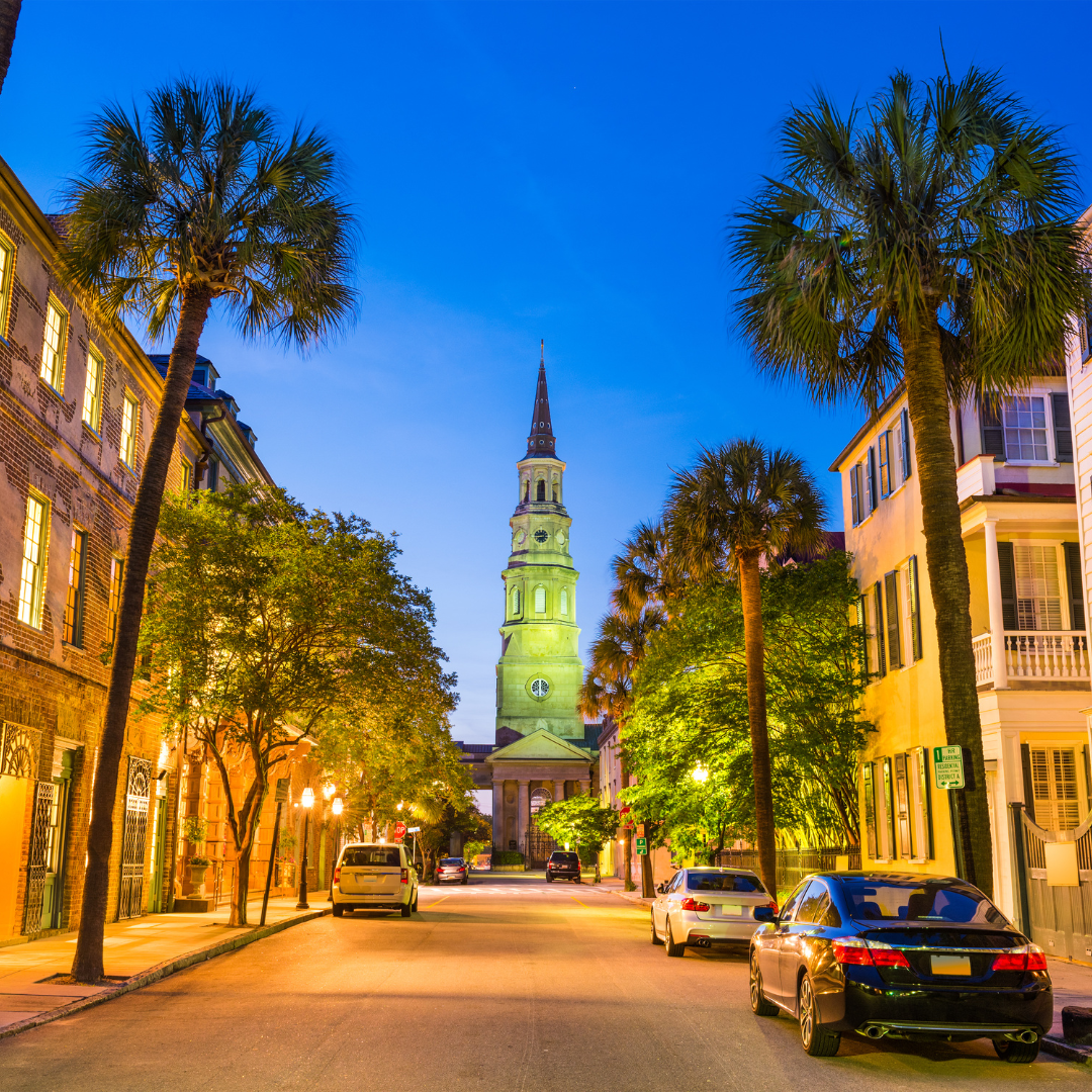 A street with cars parked on the side of it and a clock tower in the background in South Carolina.