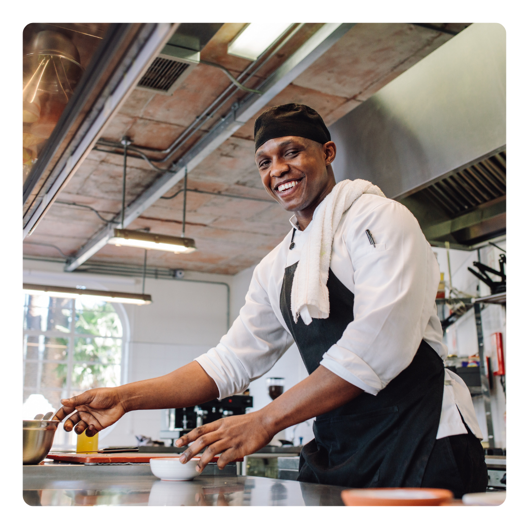 A man in an apron is preparing food in a kitchen
