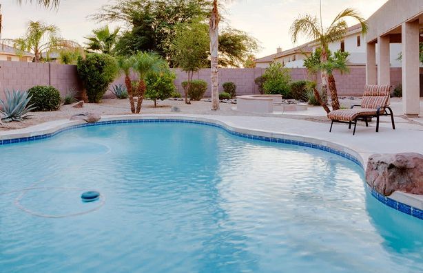Pool with clear blue water, surrounded by concrete patio and desert landscaping.