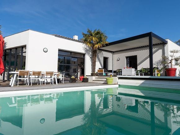 Swimming pool surrounded by green foliage under a blue sky.
