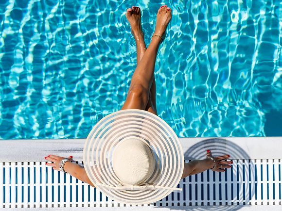 Swimming pool surrounded by green foliage under a blue sky.