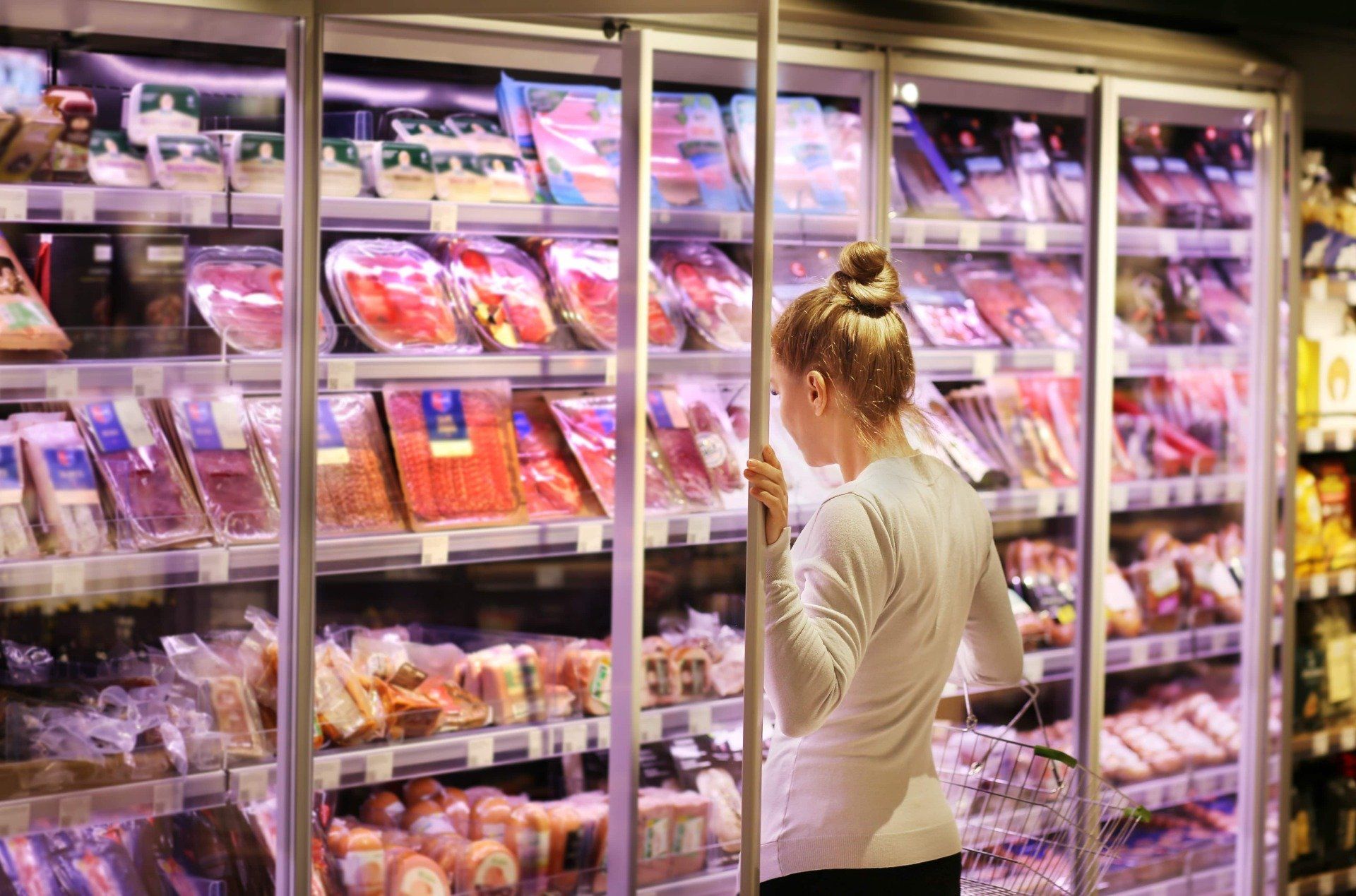 woman in supermarket looking at frozen perishable goods