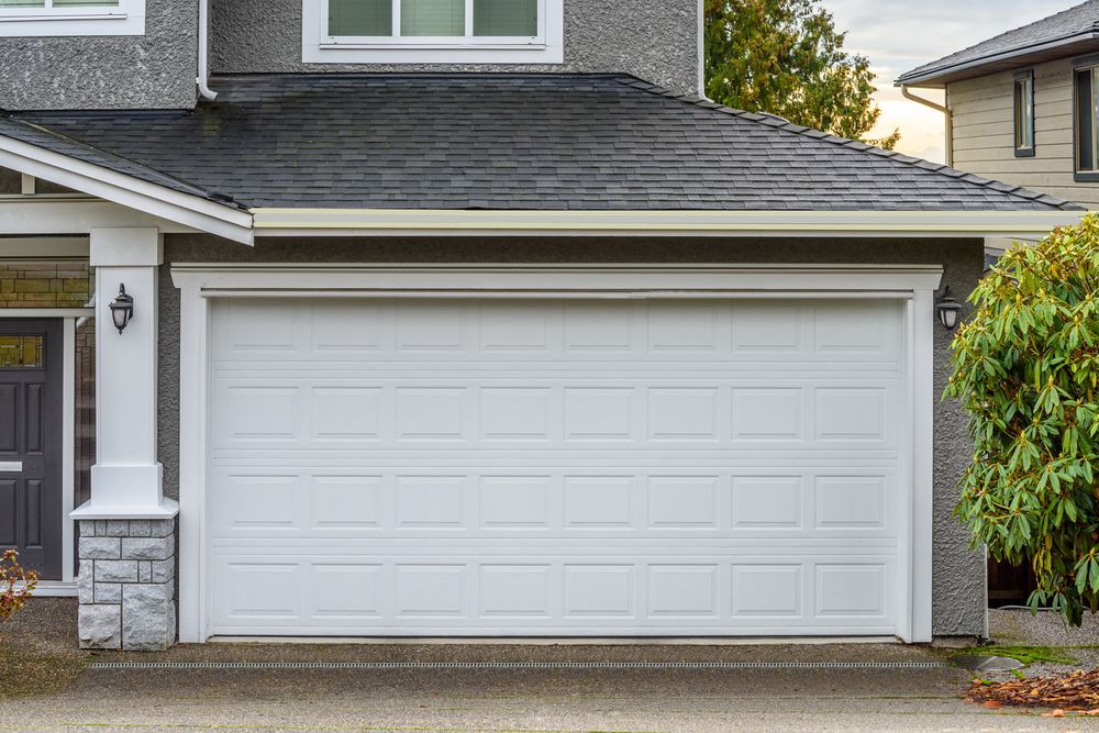 White garage door on a gray house with a dark gray roof. — Automated Garage Doors in Brassall, QLD