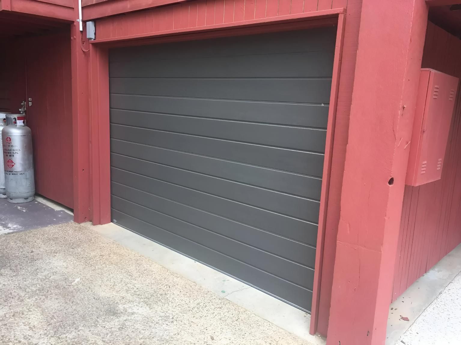 Gray Garage Door is Sitting Next to a Red Wall — Automated Garage Doors in Ipswich, QLD