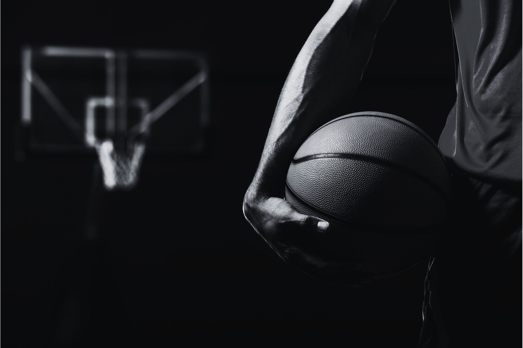 Basketball player holding a ball, court backdrop.