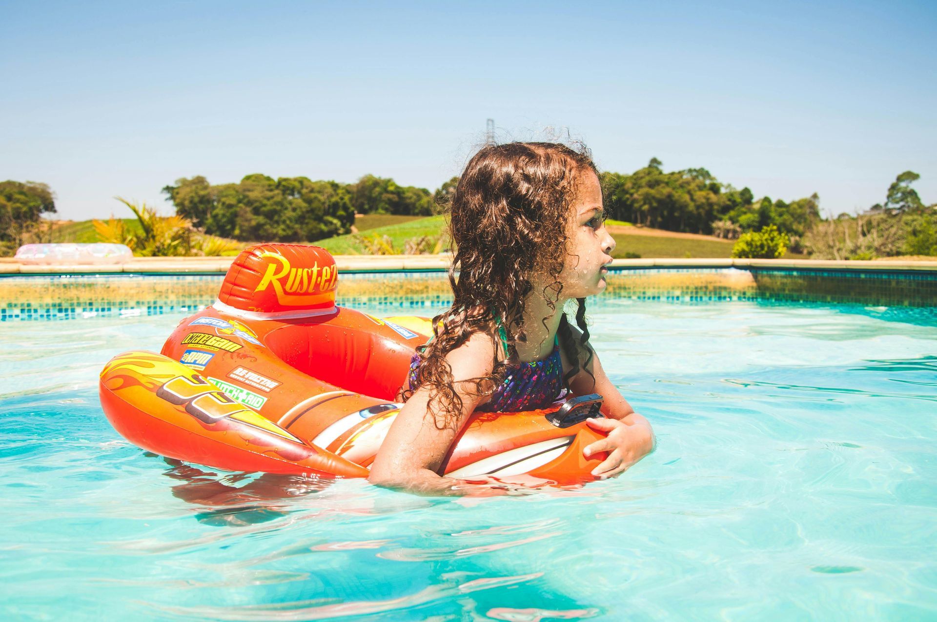 A little girl is floating on an inflatable raft in a swimming pool.