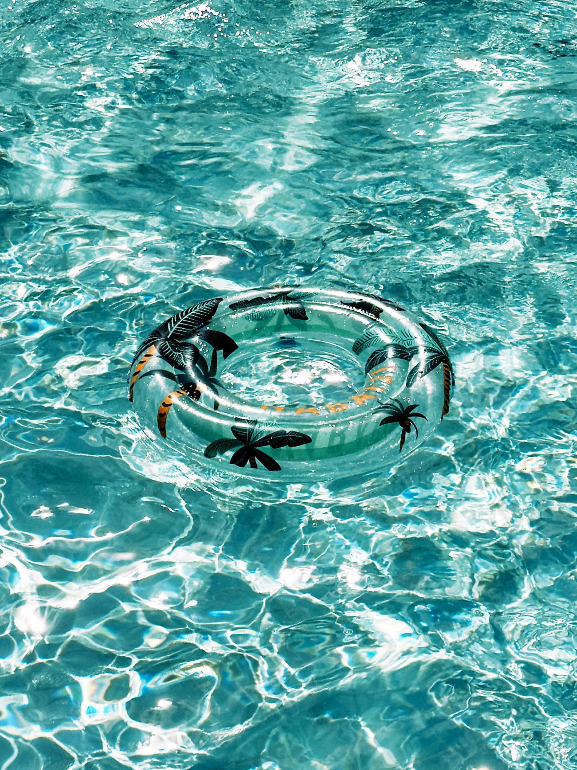 An inflatable ring with palm trees on it is floating in a swimming pool.