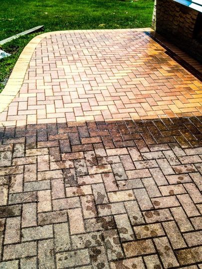 A patio shows a stark contrast between a clean, light-colored brick section and a dirty, dark, stained section.