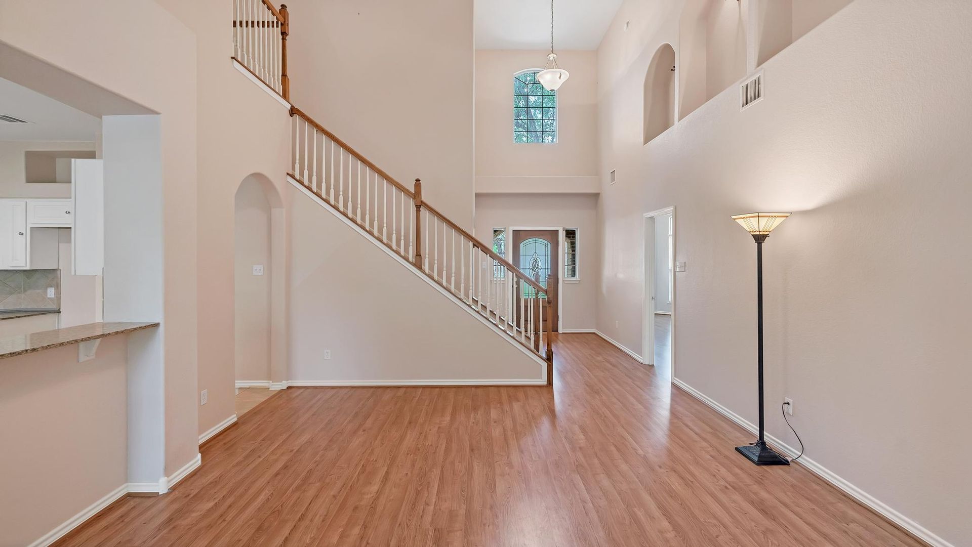 An empty living room with hardwood floors and stairs in a house.