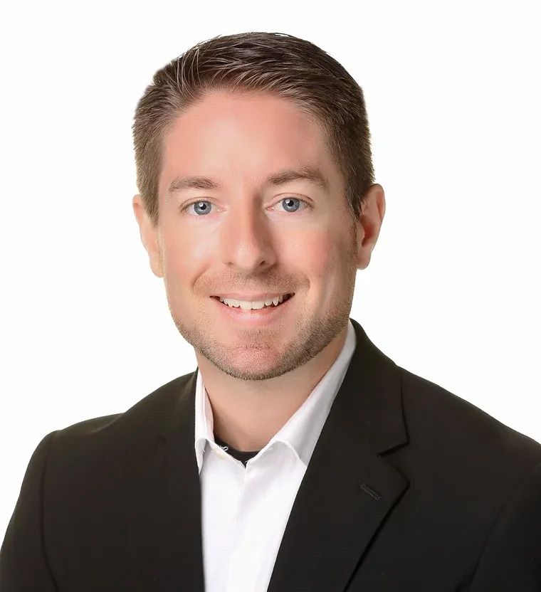 A man in a suit and white shirt is smiling for the camera.