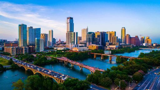 An aerial view of a city skyline with a river in the foreground and a bridge in the background.