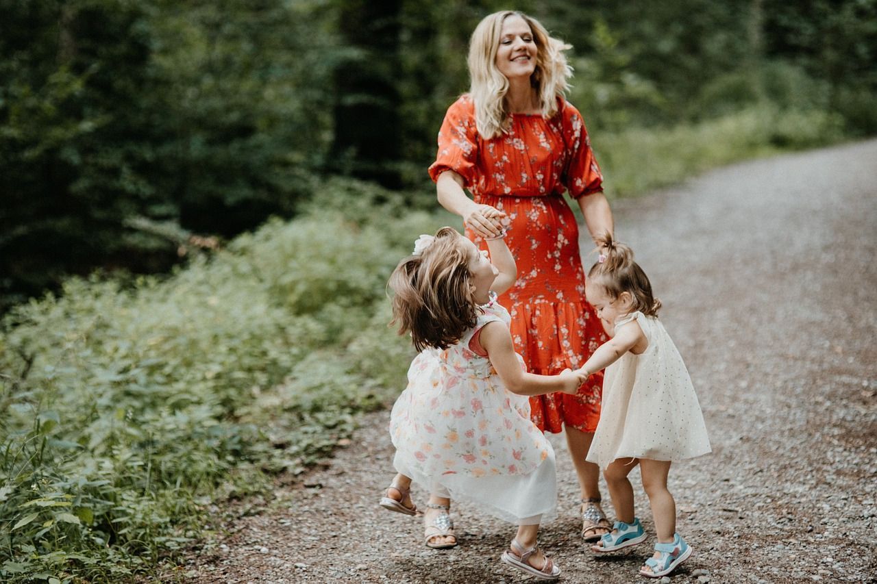 A mother plays outside with her two daughters.