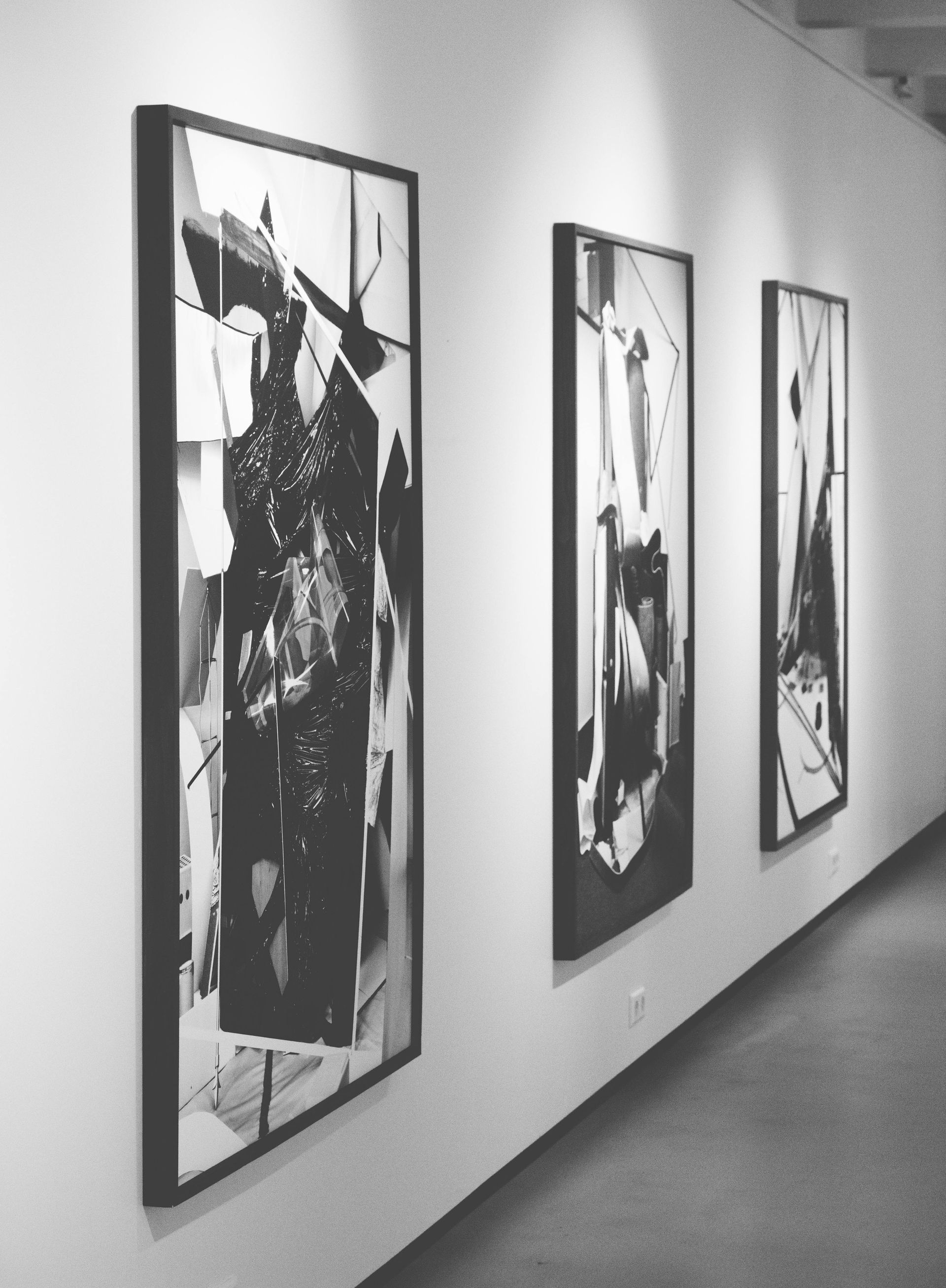 A black and white photo of three paintings on a wall