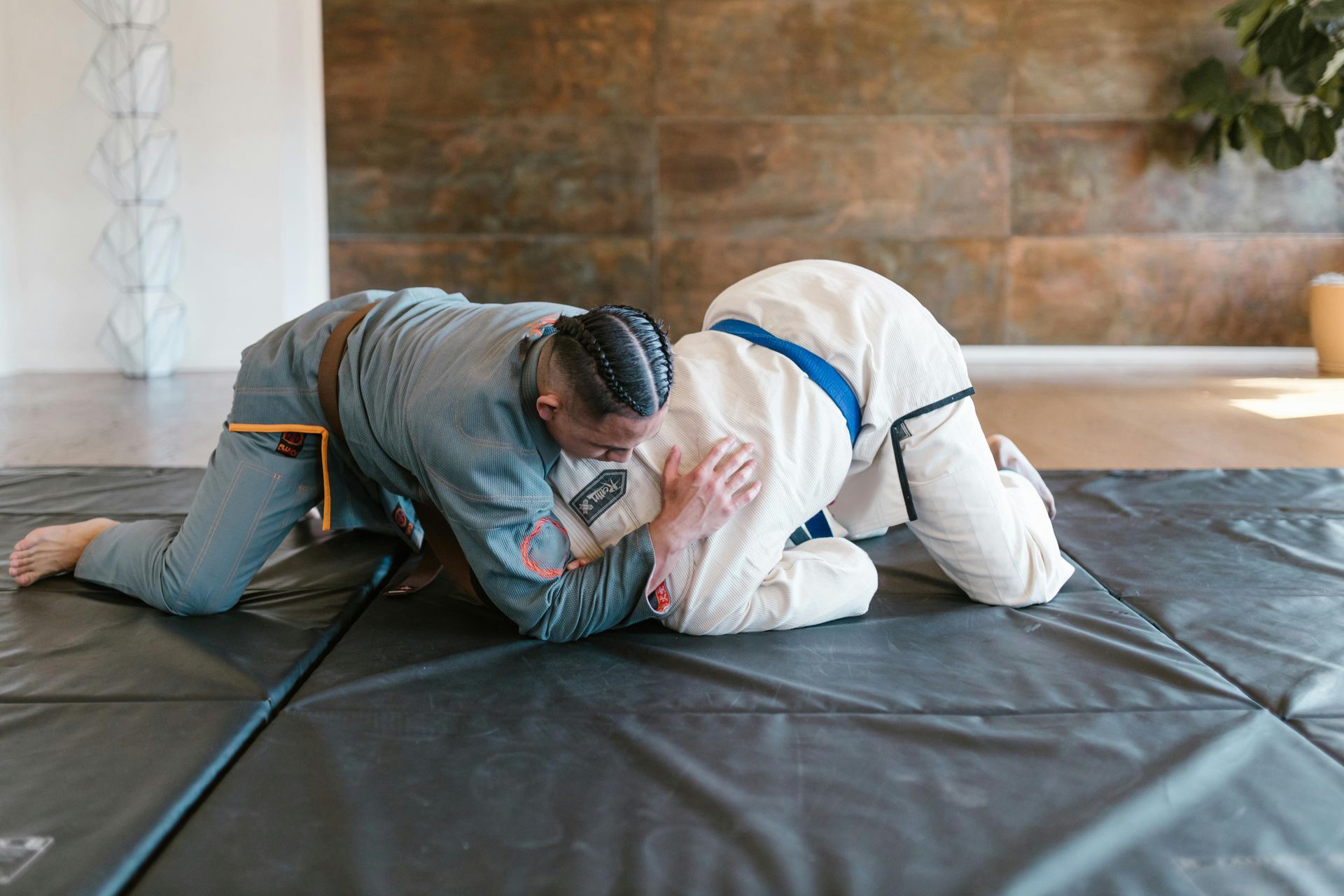 Two men are wrestling on a mat in a gym.