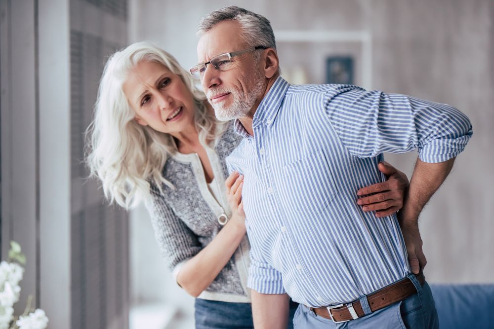 Woman Supports Man with Back Pain Indoors — Freedom Wealth Solutions in Mornington Peninsula, VIC