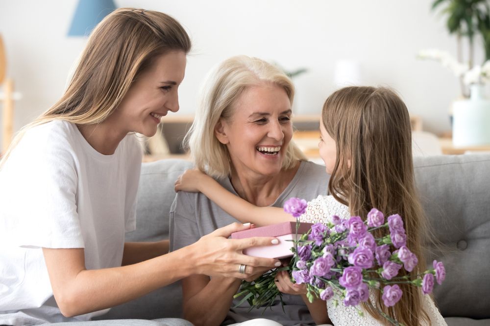 Woman and Child Give a Gift and Flowers to A Smiling Older Woman — Freedom Wealth Solutions in Mornington, VIC