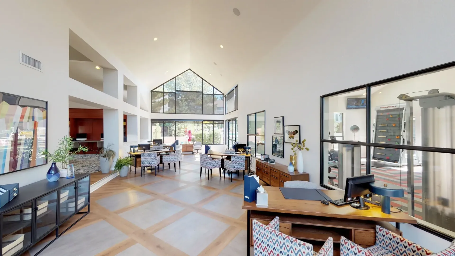 Spacious leasing office with multiple workstations and large windows overlooking greenery.