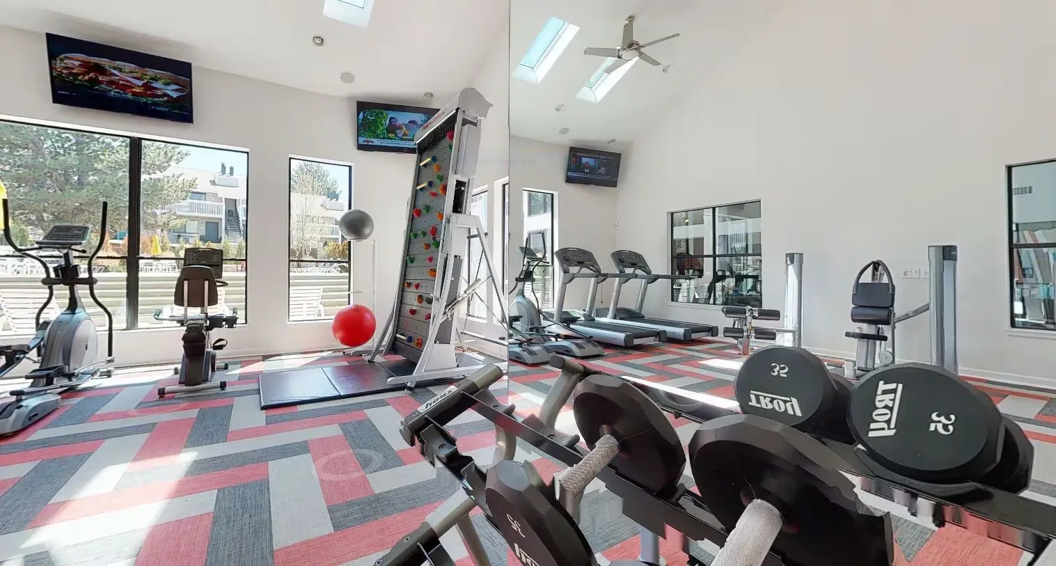 Fitness center with treadmills, ellipticals, weights, and a climbing wall.