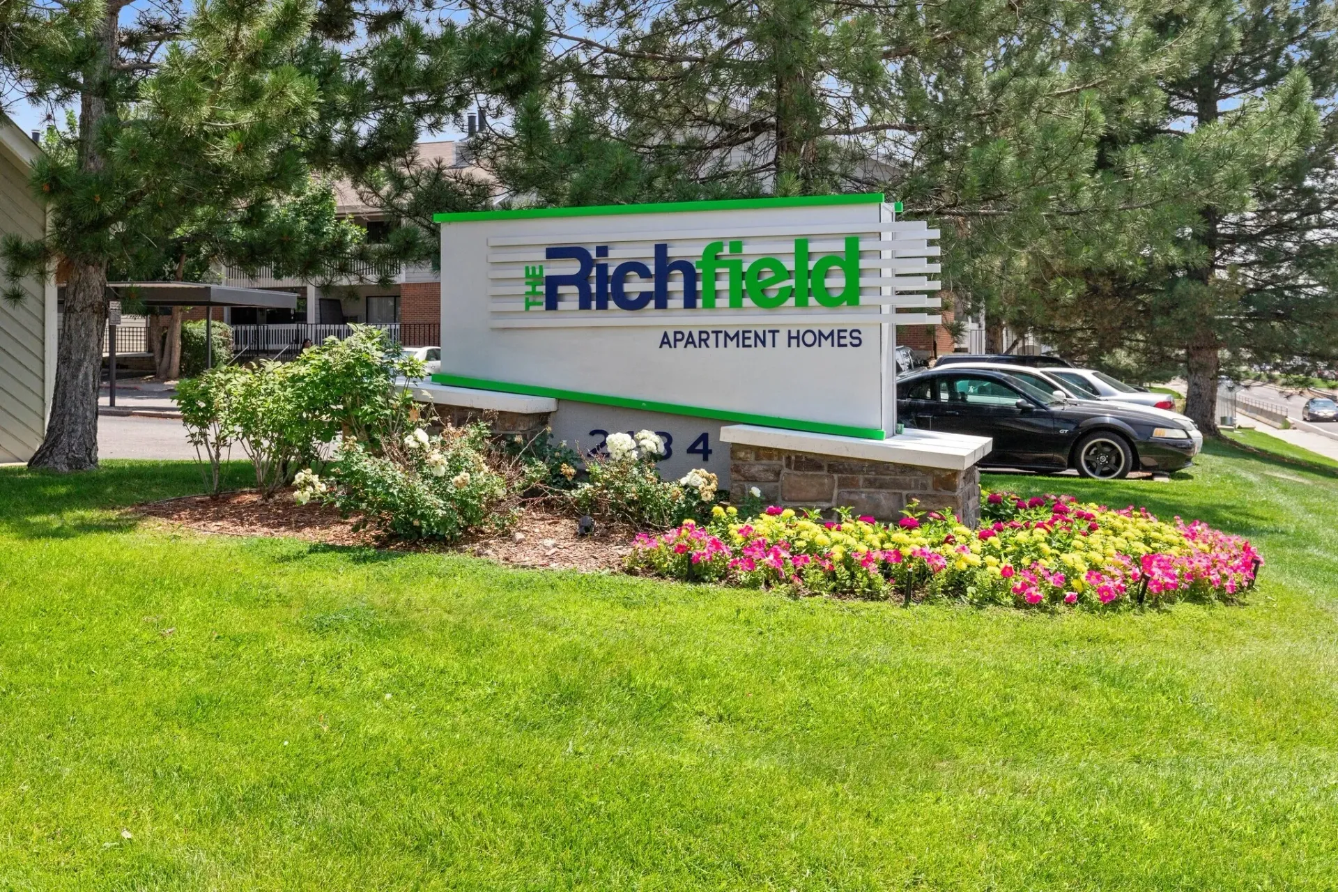 Richfield Apartment Homes monument sign with landscaping and cars in the background