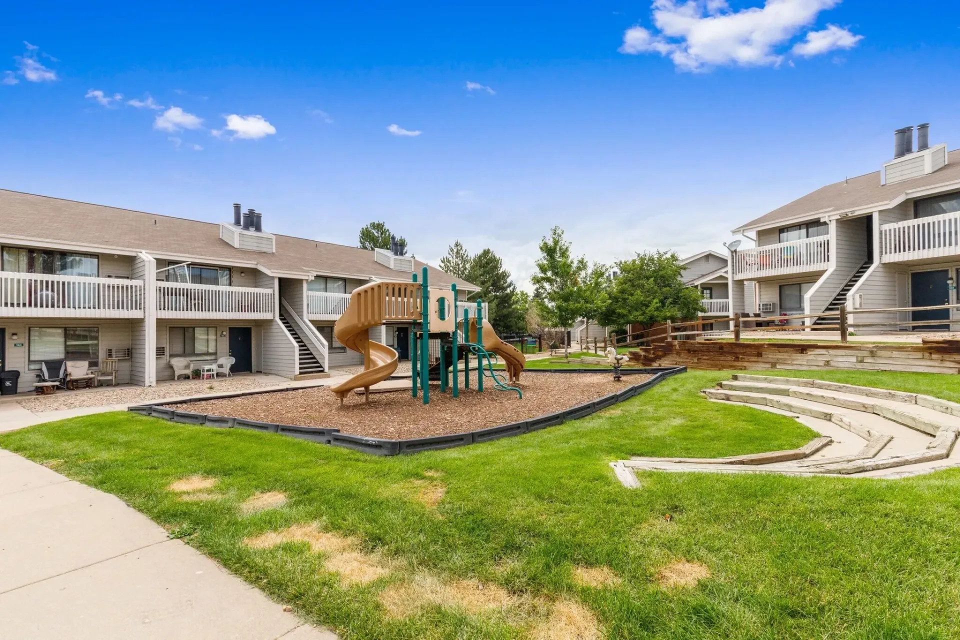 Playground and tiered seating area outside apartment buildings.