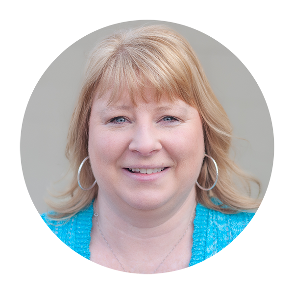 A woman wearing a blue shirt and hoop earrings is smiling in a circle.
