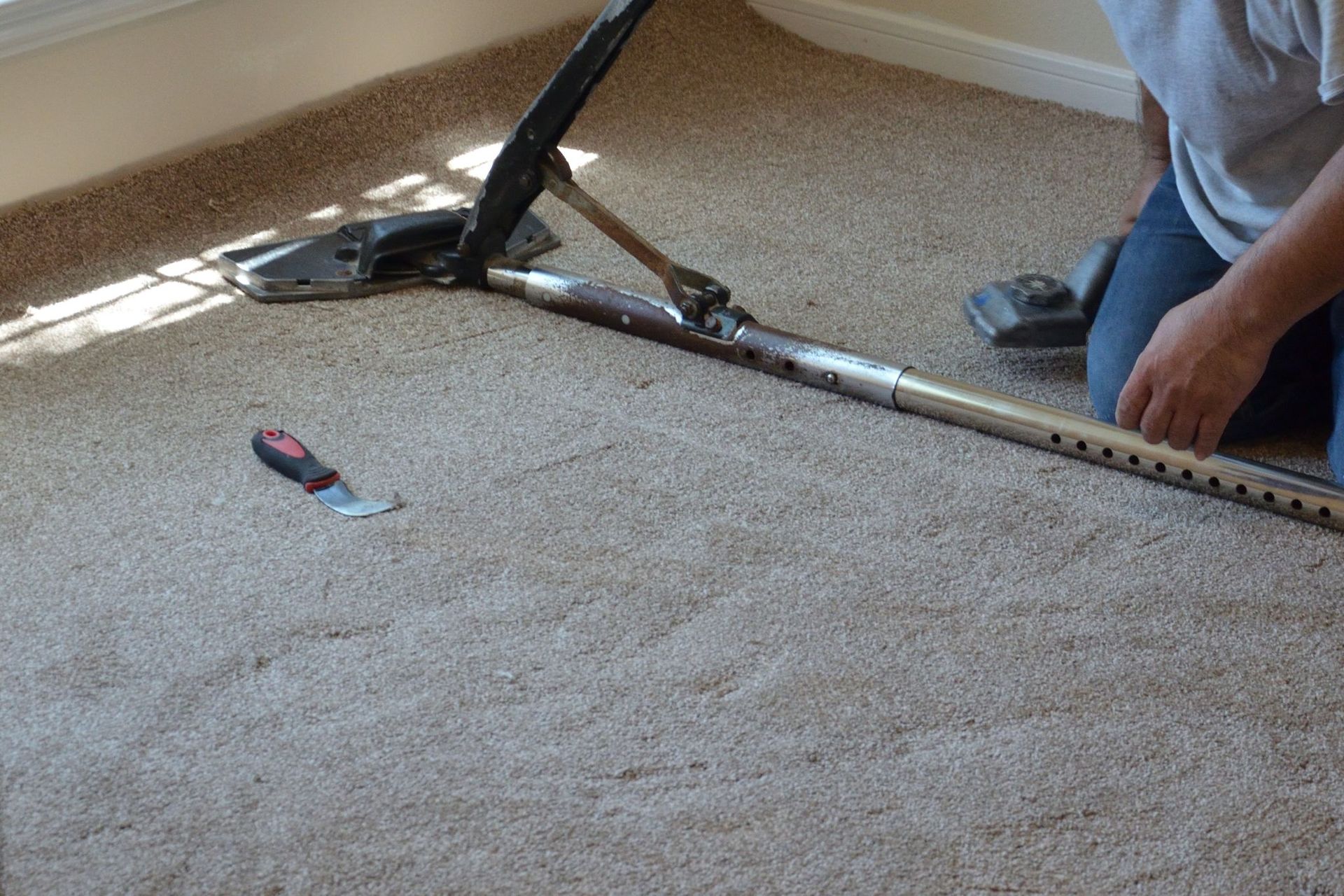 A man is laying carpet on the floor in a room