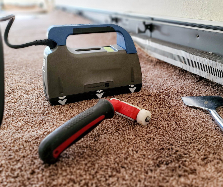 A carpet cleaner is sitting on the floor next to a tool.