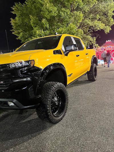 A yellow truck is parked in a parking lot at night.