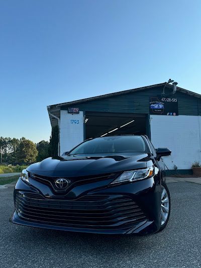 A black toyota camry is parked in front of a garage.