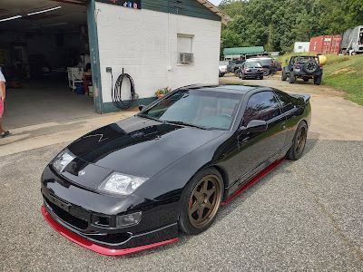 A black sports car is parked in front of a garage.