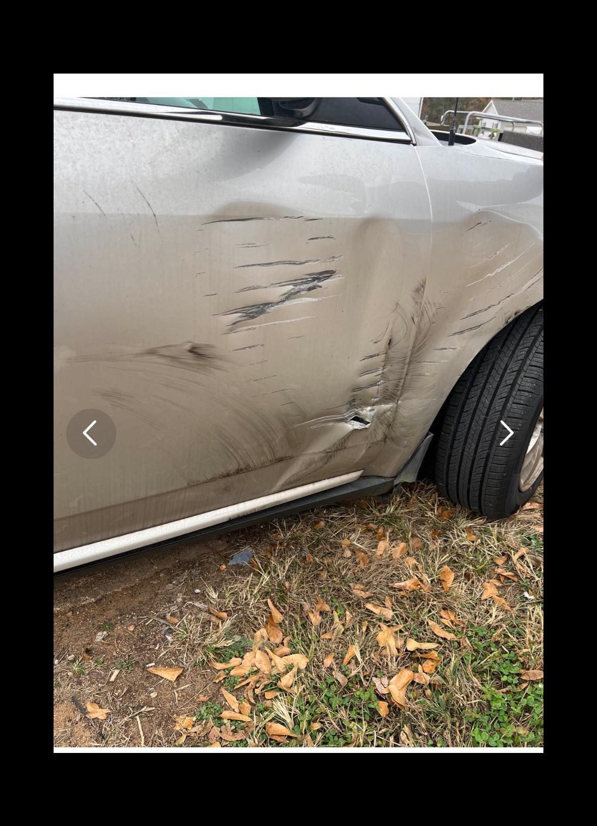 A car with a damaged side door is parked in the grass.