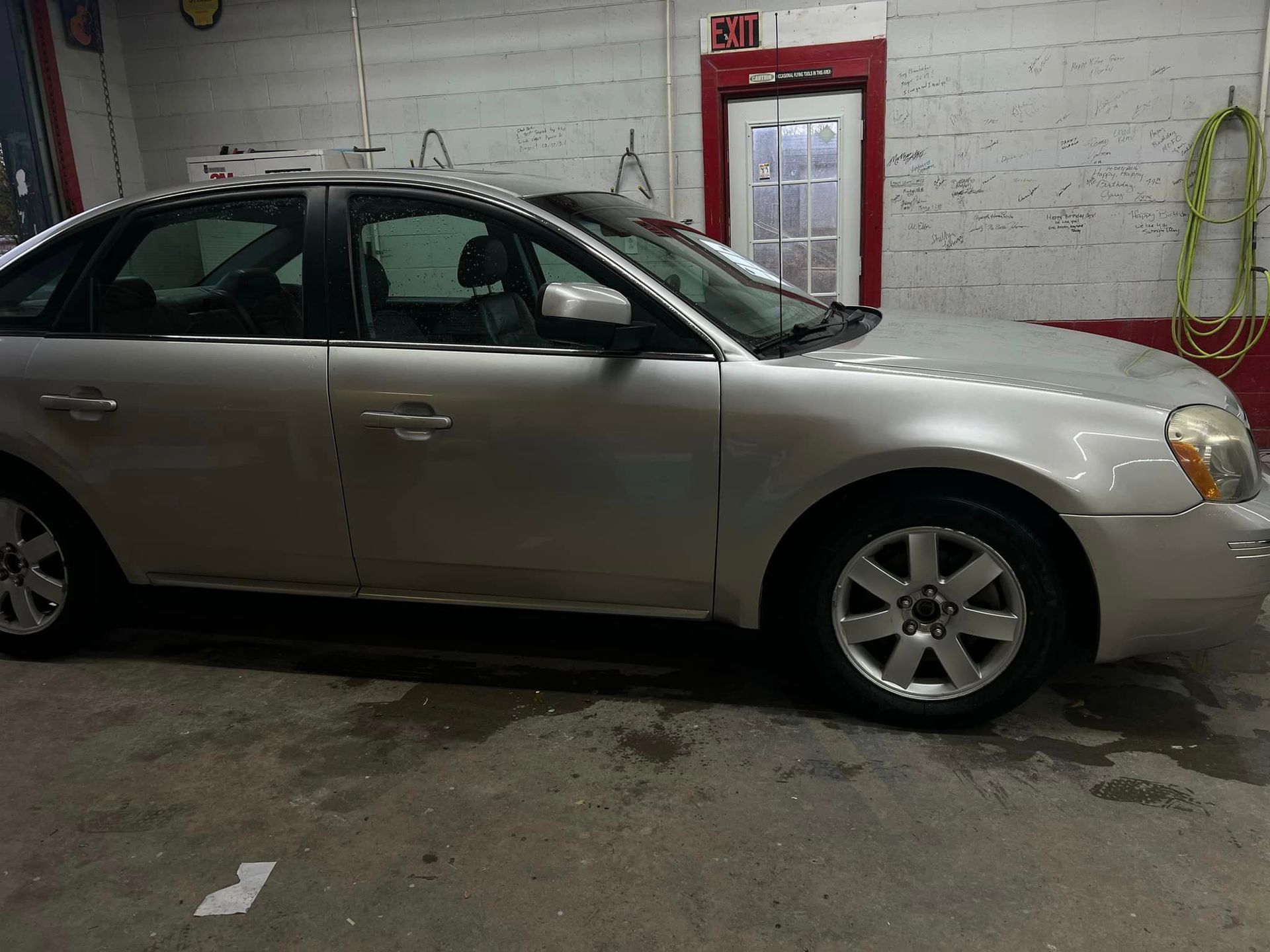 A silver car is parked in a garage next to a red door
