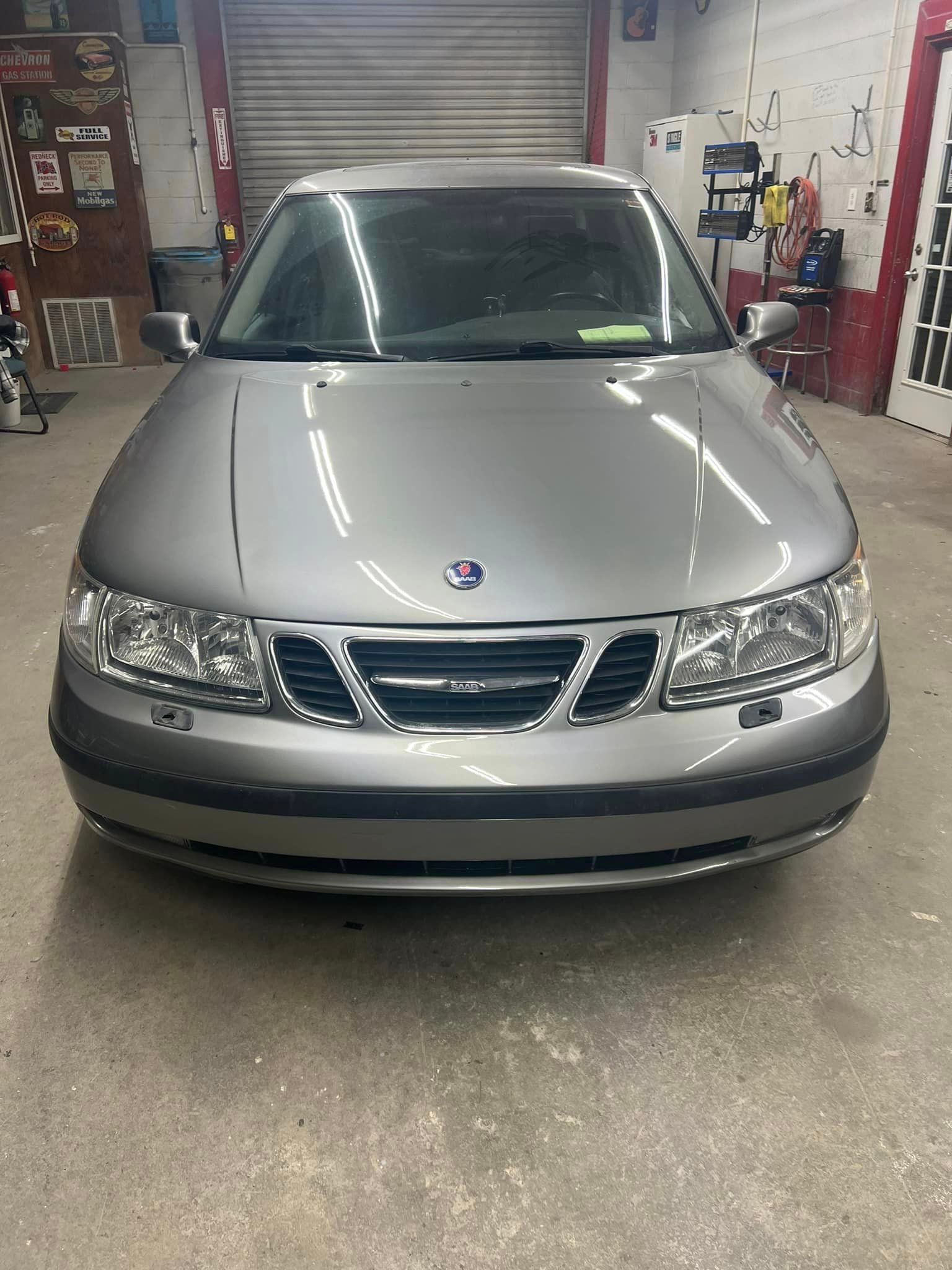 A silver saab car is parked in a garage.