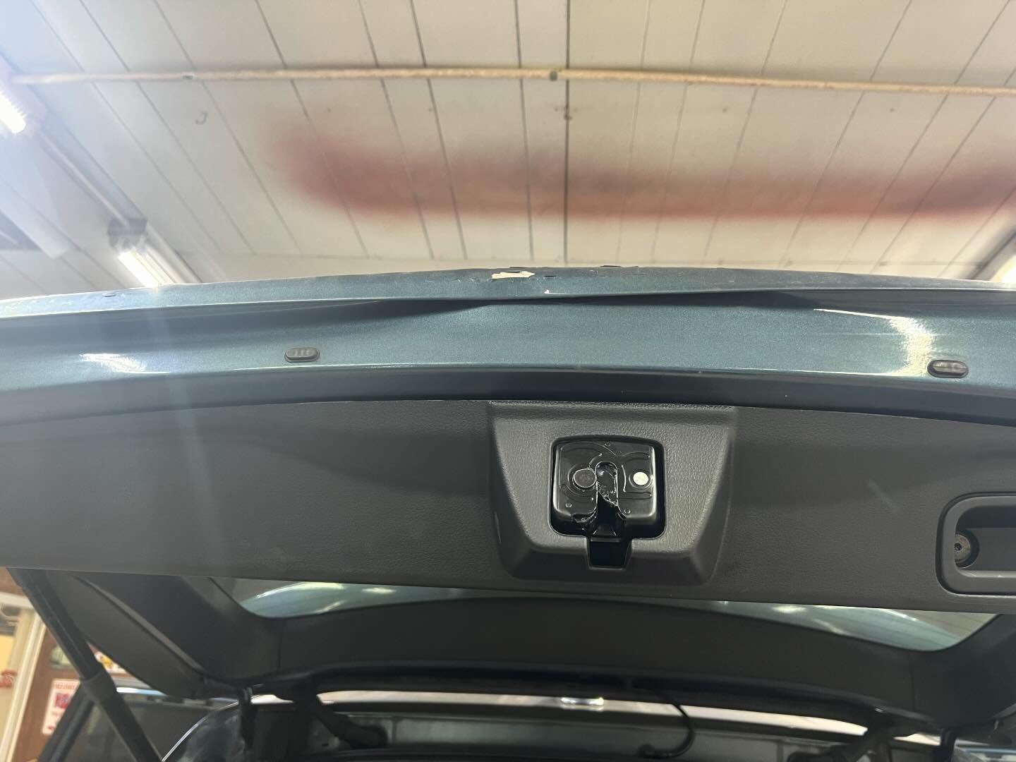 The back of a car with the trunk open in a garage.