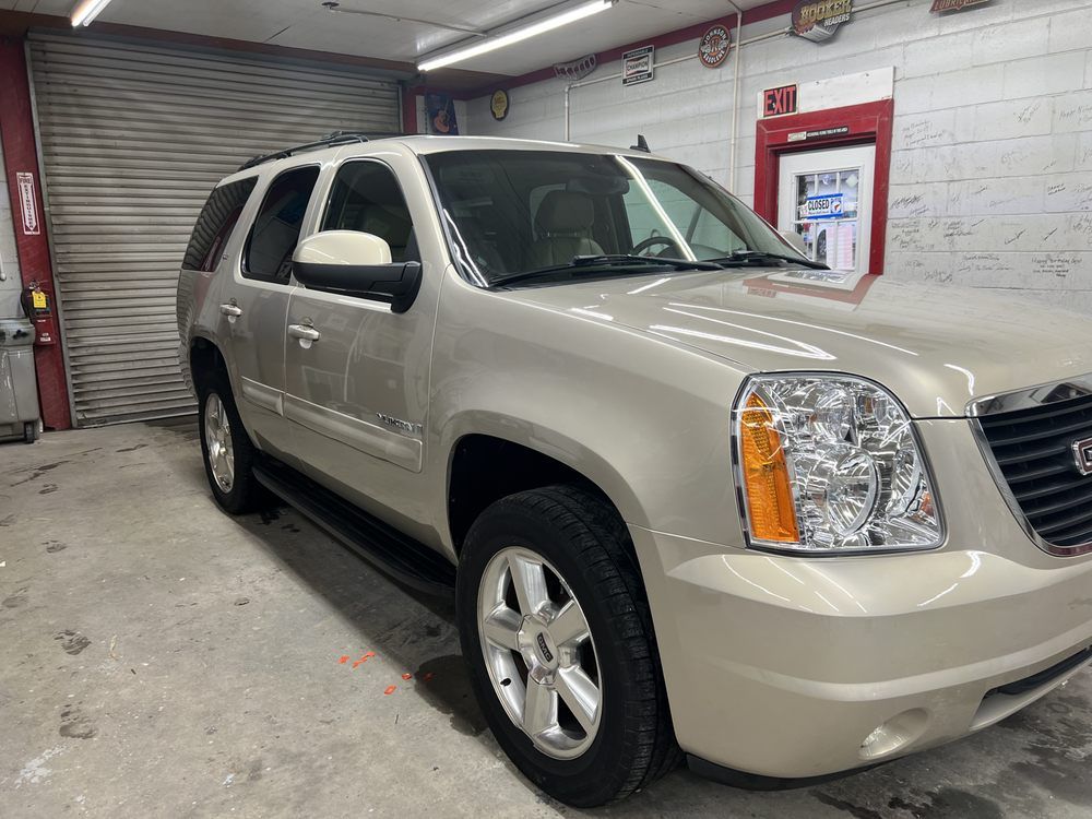A tan gmc yukon is parked in a garage.