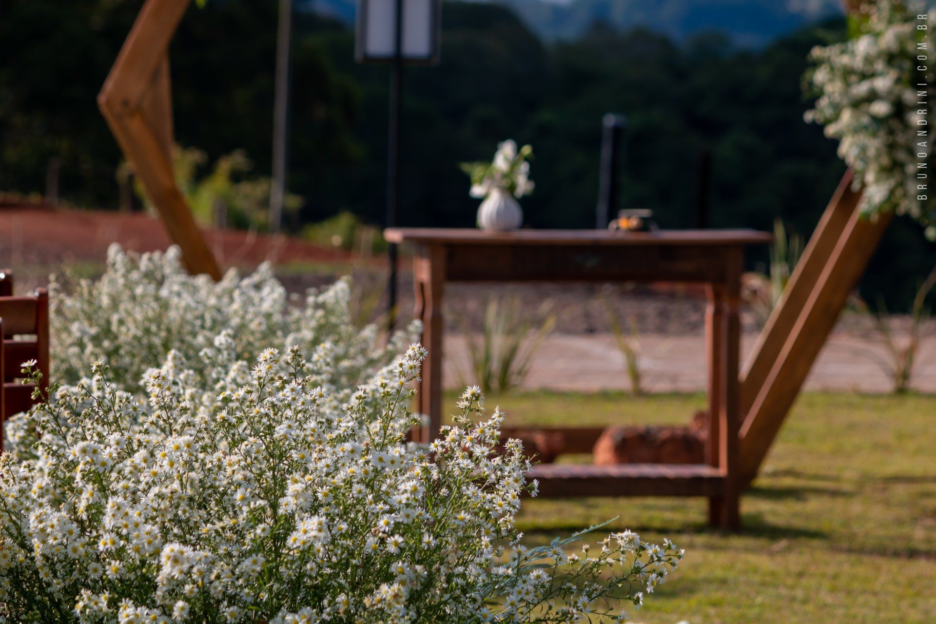 Decoração de casamento no alto da colina com móveis rústico e flores do campo.