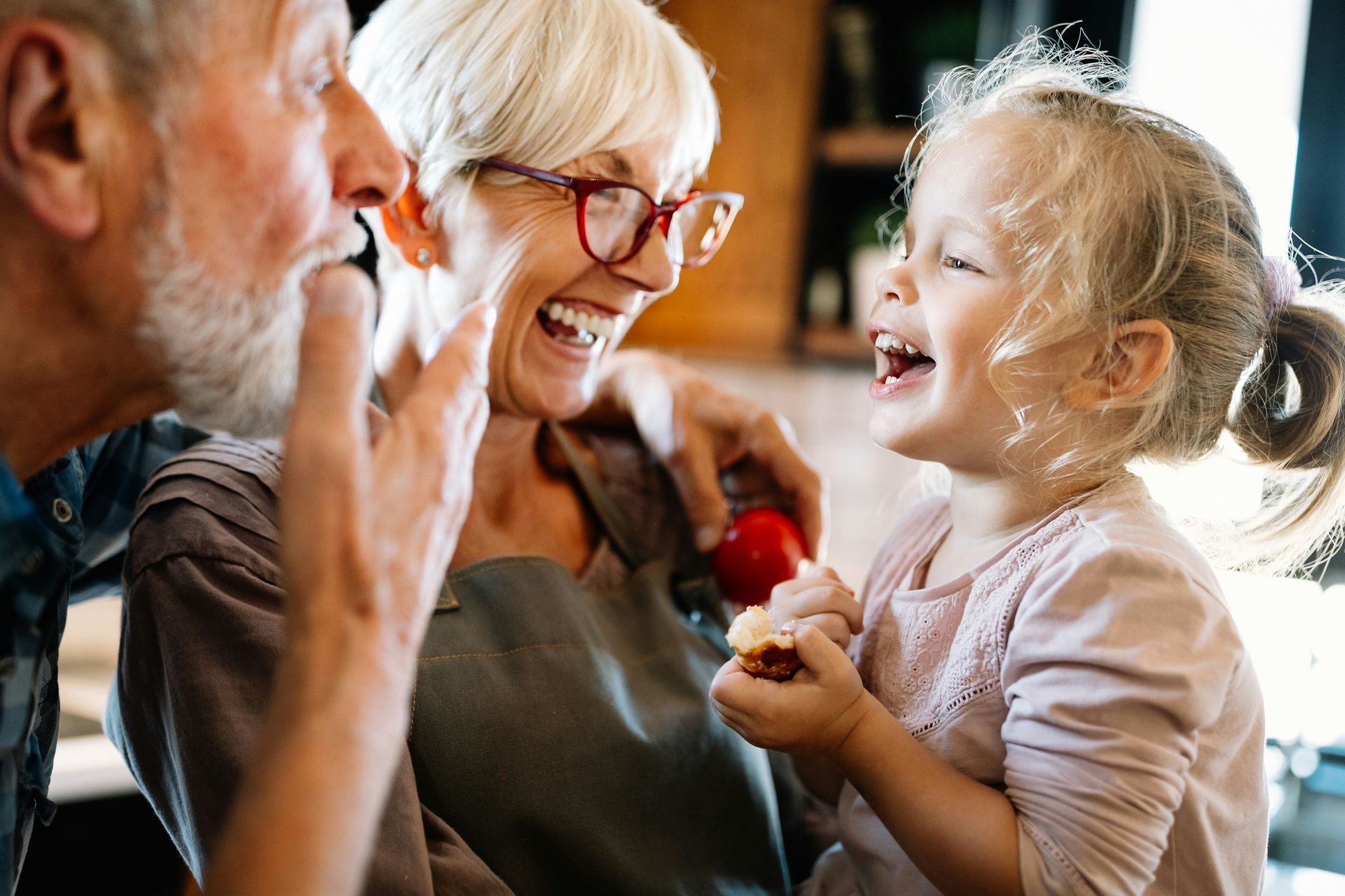 Senior couple and young child laughing together indoors.